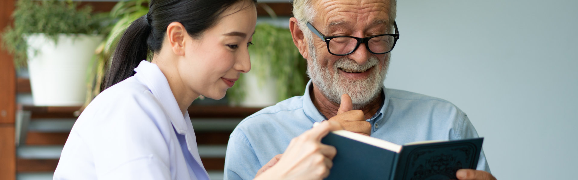 caregiver and senior man reading a book