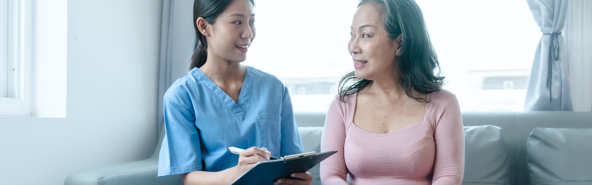 caregiver holding a clipboard and senior woman