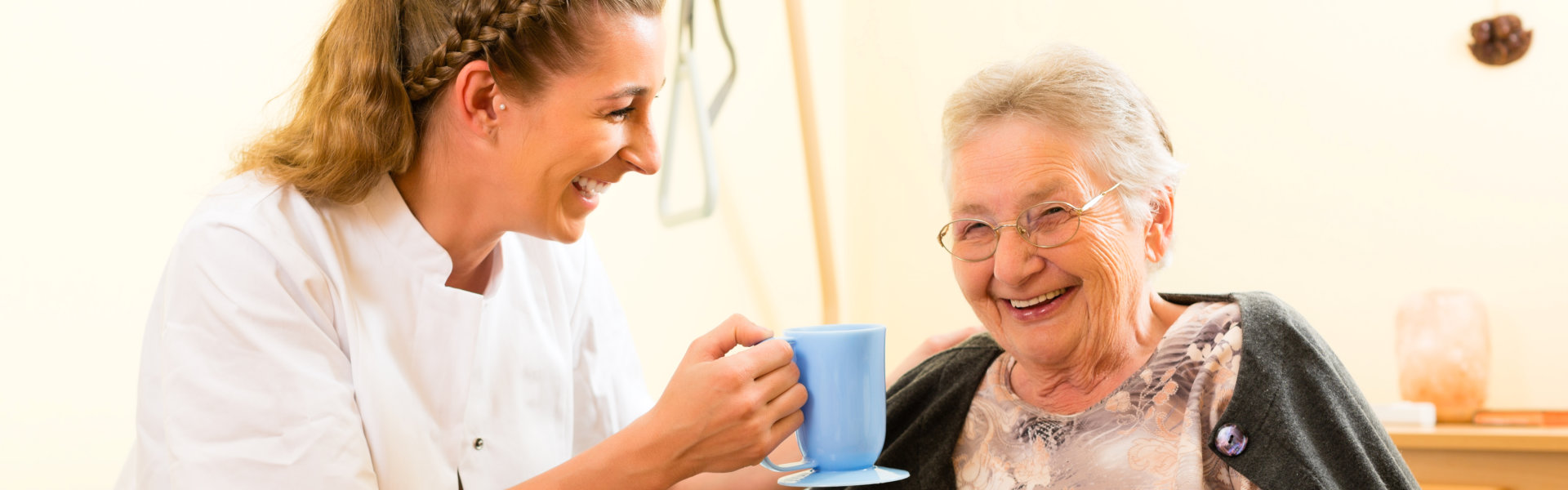 caregiver bringing a cup of water for the senior woman